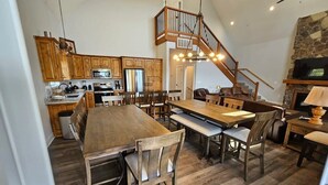 Una cocina amplia con armarios de madera, una gran mesa de comedor y una escalera que lleva a un nivel superior.