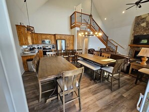 A spacious kitchen with wooden cabinets, a large dining table, and a staircase leading to an upper level. - Mtn Paradise Lake view Indoor/Outdoor pools/2 splash pads, Silver Dollar City (Branson)