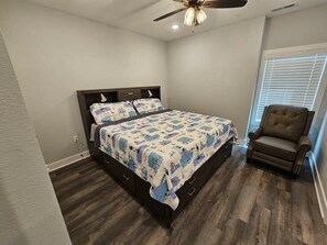 A bedroom with a bed, a chair, a ceiling fan, and a window with blinds. - Mtn Paradise Lake view Indoor/Outdoor pools/2 splash pads, Silver Dollar City (Branson)
