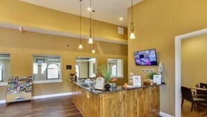 Una zona de recepción con mostrador de madera, televisor montado en la pared y ventana con vistas al exterior.