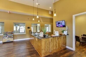 A reception area with a wooden counter, a television mounted on the wall, and a window with a view of the outside. - Mtn Paradise Lake view Indoor/Outdoor pools/2 splash pads, Silver Dollar City (Branson)