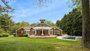 A large, two-story house with a wrap-around porch, a swimming pool, and a well-maintained lawn. - St. Michaels Escape | Pool, Hot Tub & Fire Pit (Saint Michaels)
