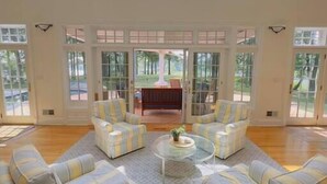 A spacious living room with a high ceiling, large windows, and a view of the outdoors. - St. Michaels Escape | Pool, Hot Tub & Fire Pit (Saint Michaels)