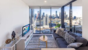 A modern living room with a large window, a sofa, a coffee table, and a TV.