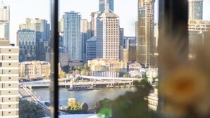 A city skyline with modern high-rise buildings and a river in the foreground.