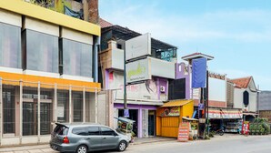 A street view with a car parked on the side, various shops, and a building with a sign that reads "geuls".