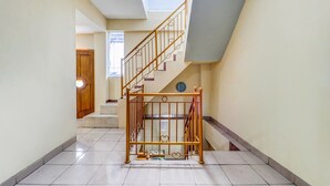 A hallway with a staircase, a metal gate, and a clock on the wall.