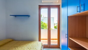 A bedroom with a bed, a blue wardrobe, and a sliding glass door leading to a balcony. - Friendly Family Apartment at Ischia (Ischia)