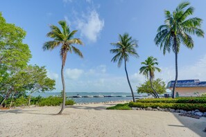 A beach with palm trees, a clear sky, and boats in the water. - Key Largo Getaway w/ Bay Views + Pool Access! (Key Largo)