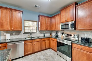 A kitchen with wooden cabinets, a dishwasher, a microwave, an oven, and a toaster.