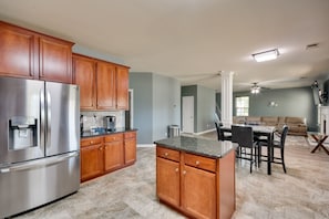 A modern kitchen with wooden cabinets, a stainless steel refrigerator, and a marble countertop. - Fort Mitchell Vacation Rental w/ Home Office! (Fort Mitchell)