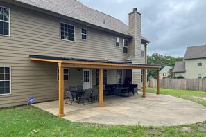 A two-story house with a covered patio area featuring outdoor furniture.