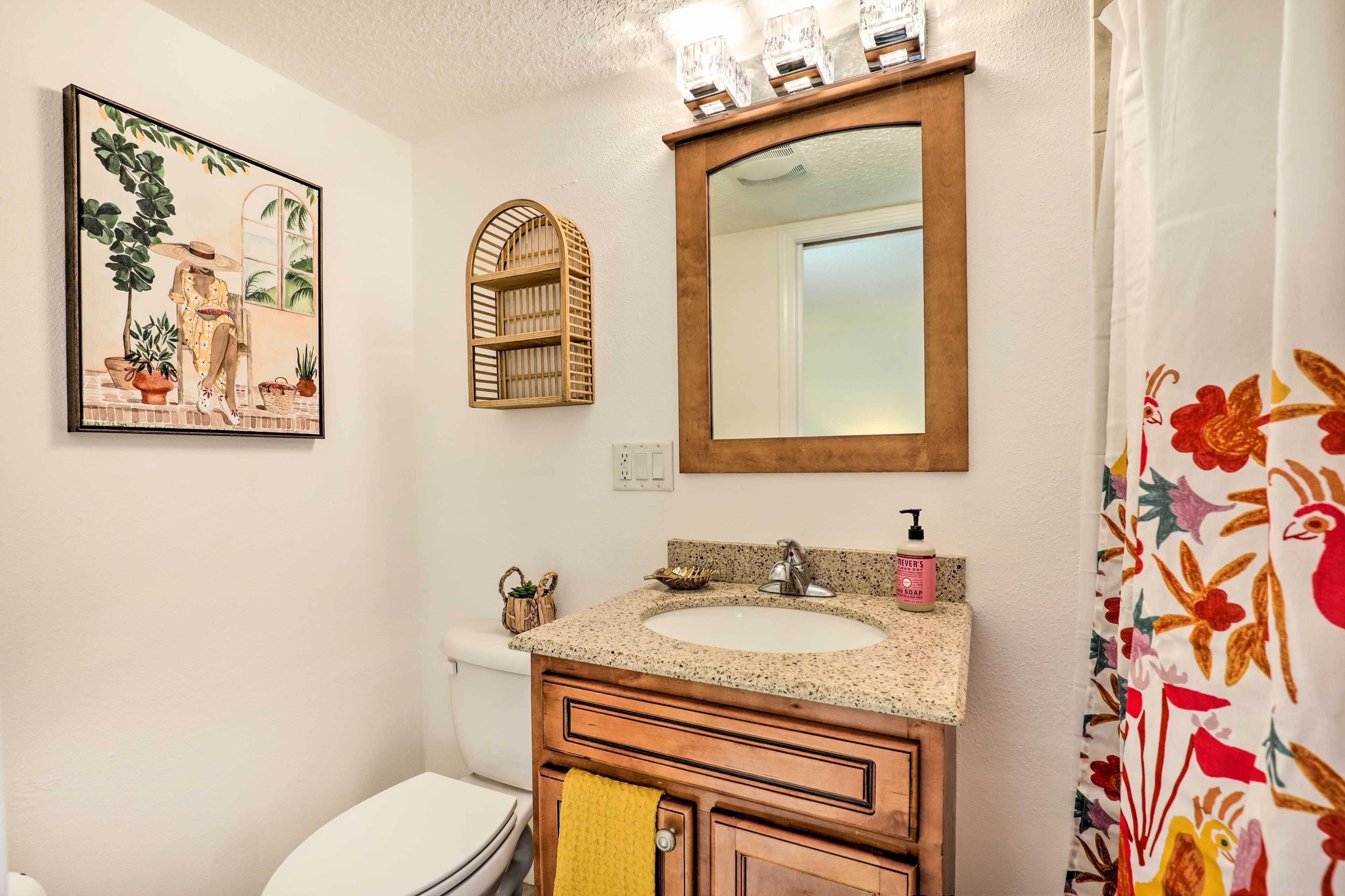 Ein Badezimmer mit Waschbecken, Spiegel, Toilette und einem gerahmten Bild an der Wand.