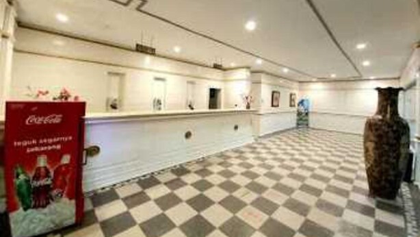 Un hall de hotel con suelo a cuadros, una recepción y un refrigerador de Coca-Cola.
