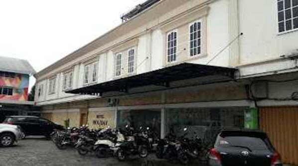 A building with a covered entrance, parked motorcycles, and a sign that reads "MAZDA". - EXPRESS O 91674 Penginapan Bm Prima (Mandau)