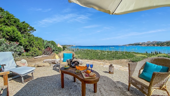 A table set outdoors with food and drinks, overlooking a coastal view.