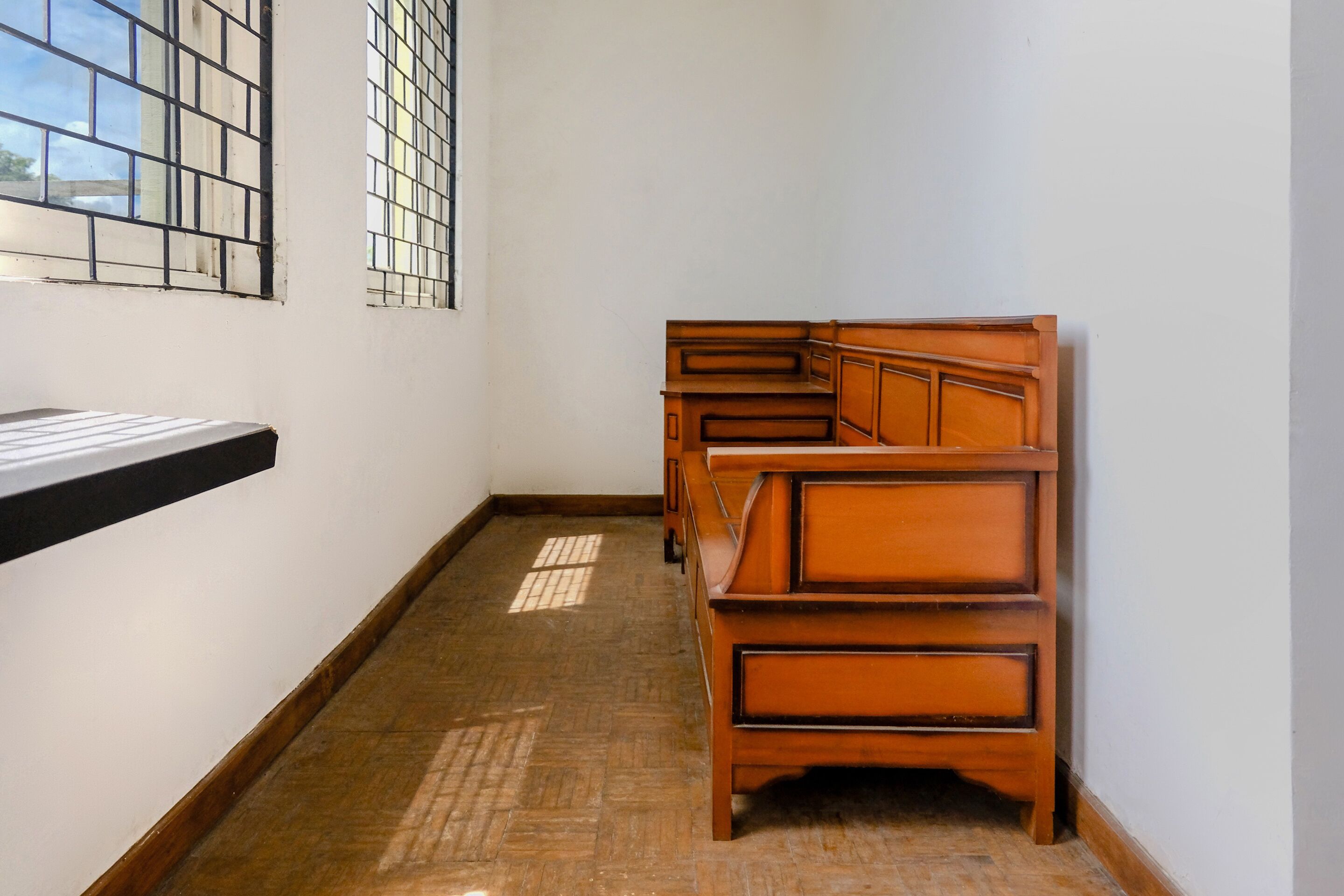 Quarto com escrivaninha de madeira e janela com padrão quadriculado.