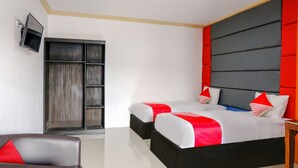 Une chambre d’hôtel moderne avec un grand lit, un téléviseur fixé au mur et une armoire.