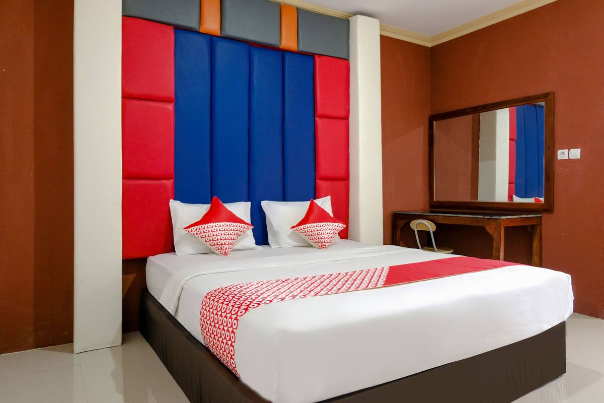 Een moderne hotelkamer met een groot bed, een houten nachtkastje en een spiegel.