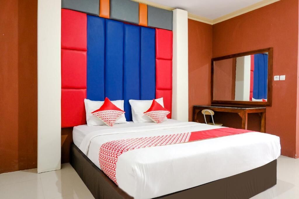 Een hotelkamer met een bed, een bureau en een spiegel.