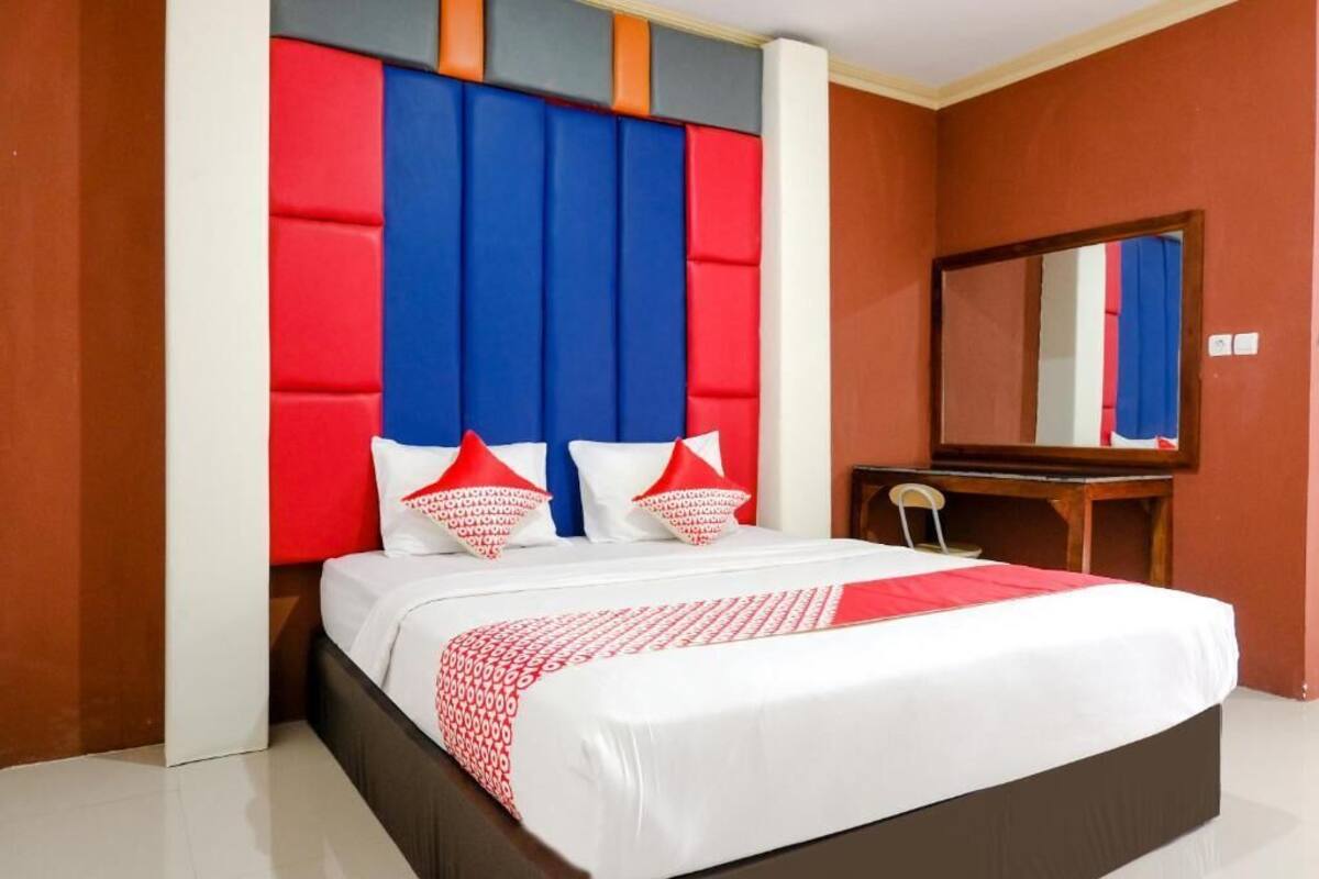 Een hotelkamer met een bed, een bureau en een spiegel.
