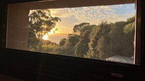 Et vindue med udsigt til en solnedgang over et skovlandskab.