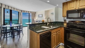 Una cocina moderna con encimeras de granito, armarios de madera y un horno negro.