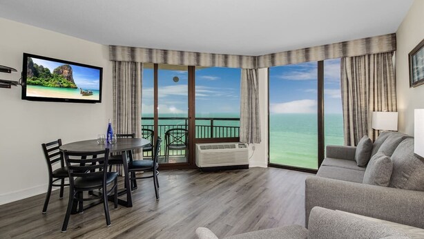 Una habitación de hotel con balcón, comedor y sala de estar.