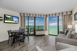 Une chambre d’hôtel avec balcon, un coin repas et un espace salon.