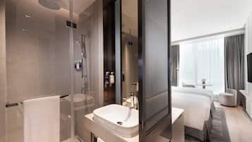 A modern hotel bathroom with a glass-enclosed shower, a large sink, and a visible mirror.