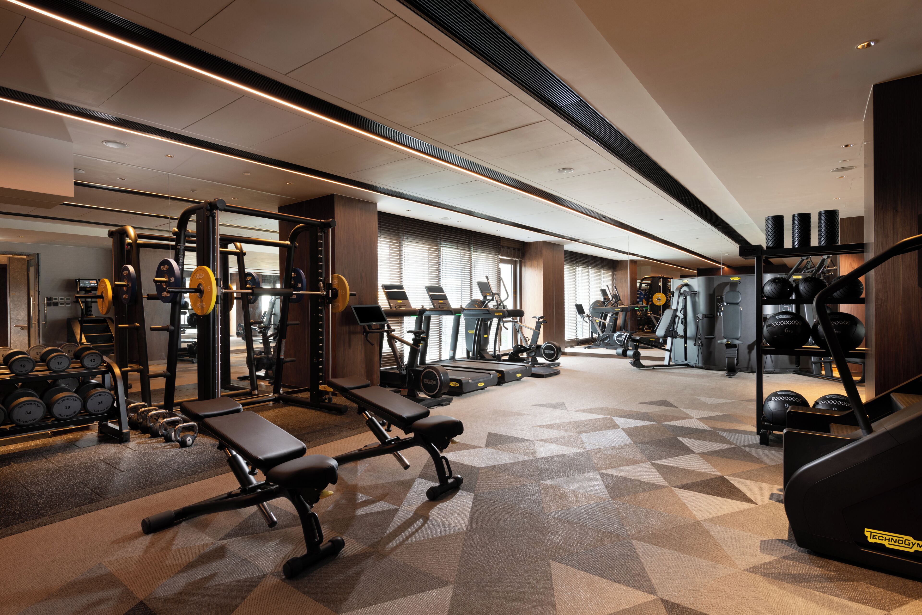 A gym with various exercise equipment, including benches, dumbbells, and treadmills.