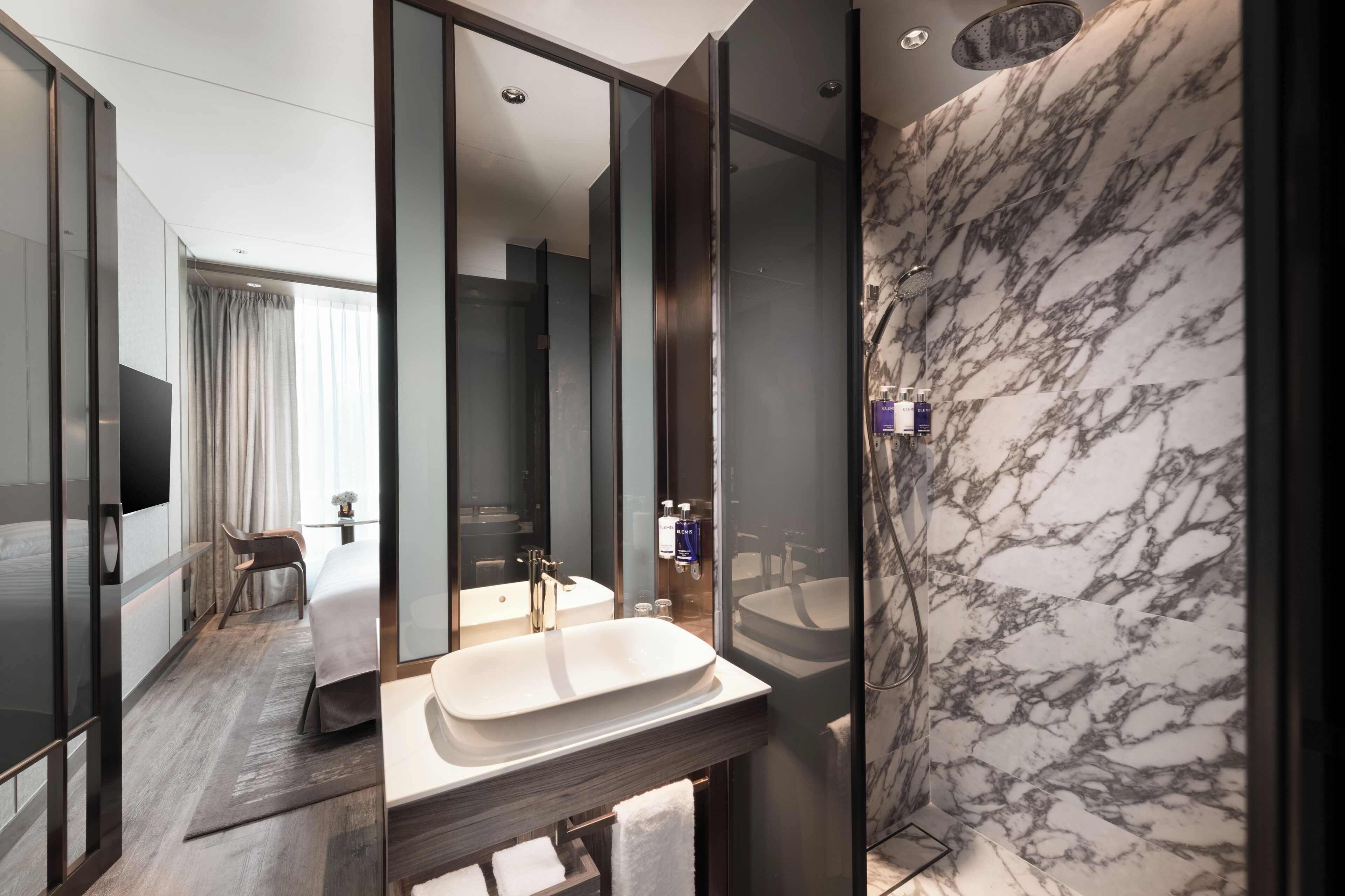 Un baño moderno con un espejo grande, un lavamanos y una ducha.