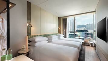 Ett hotellrum med två sängar, en TV, ett litet bord med en stol och utsikt över staden.