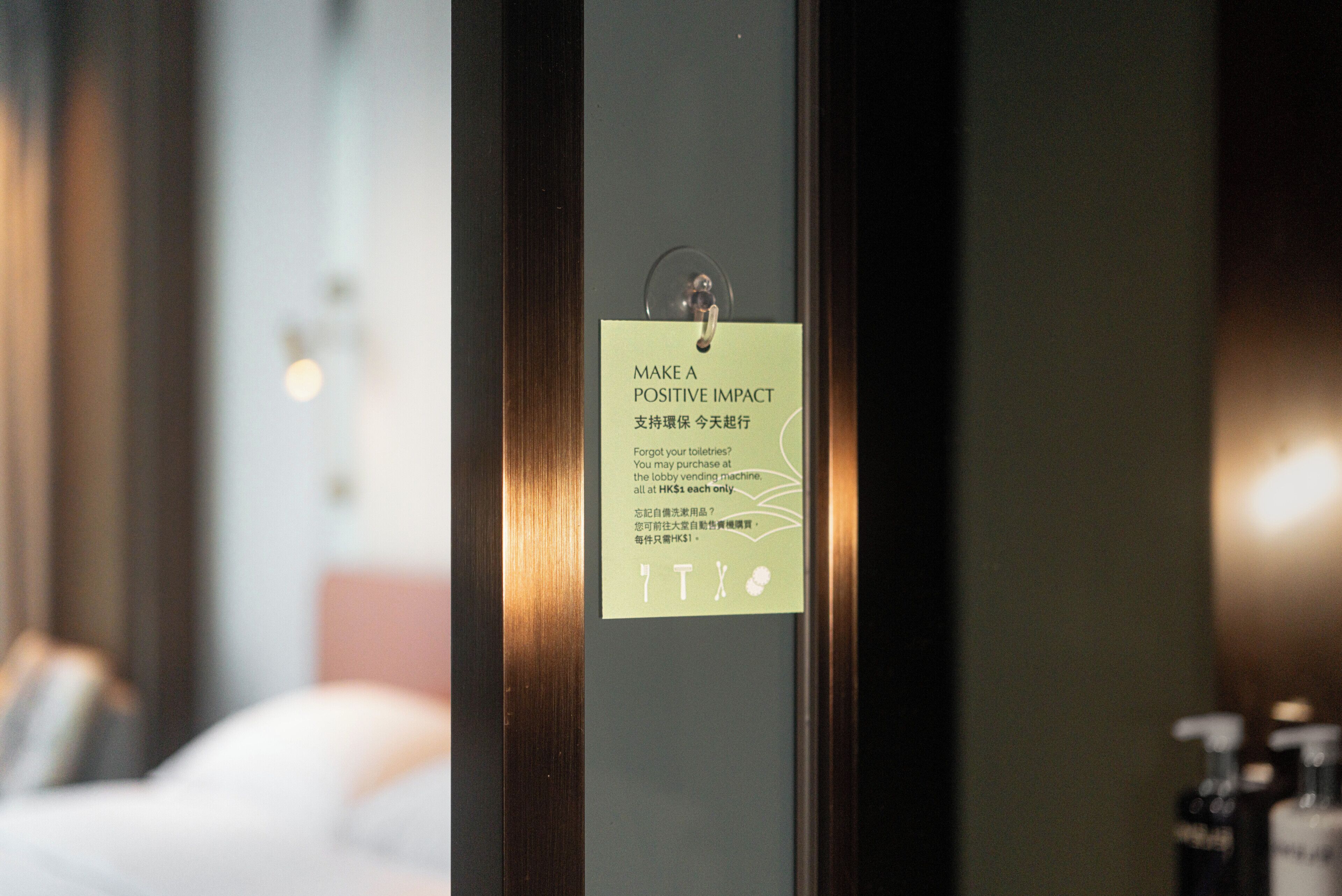 A hotel room door with a sign that reads 'MAKE A POSITIVE IMPACT' and mentions a lobby vending machine.