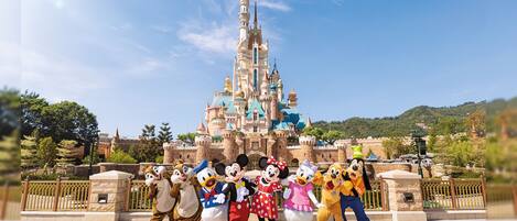 Un grupo de personajes de Disney frente a un castillo bajo un cielo despejado.