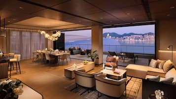 A spacious living area with a dining setup, comfortable seating, and a large window offering a city and water view.