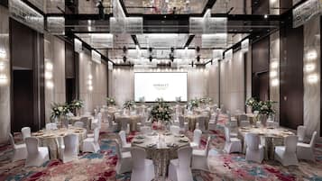 A banquet hall with round tables, white chairs, floral centerpieces, and a large screen displaying the name "DORSETT".