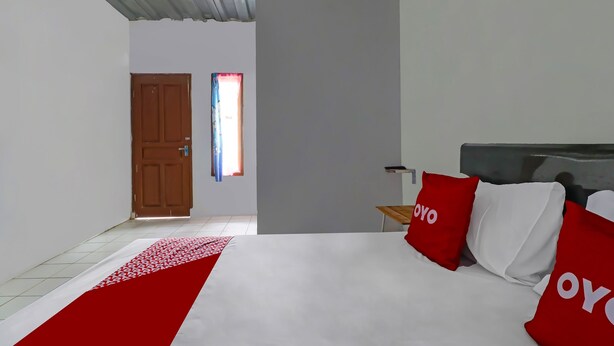 Un dormitorio con una cama, una puerta de madera, una ventana con cortinas y una mesita de noche.
