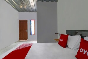 Een slaapkamer met een bed, een houten deur, een raam met gordijnen en een nachtkastje.