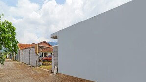 Una zona residencial con una calle larga y recta, un muro blanco y una casa con techo de tejas rojas al fondo.