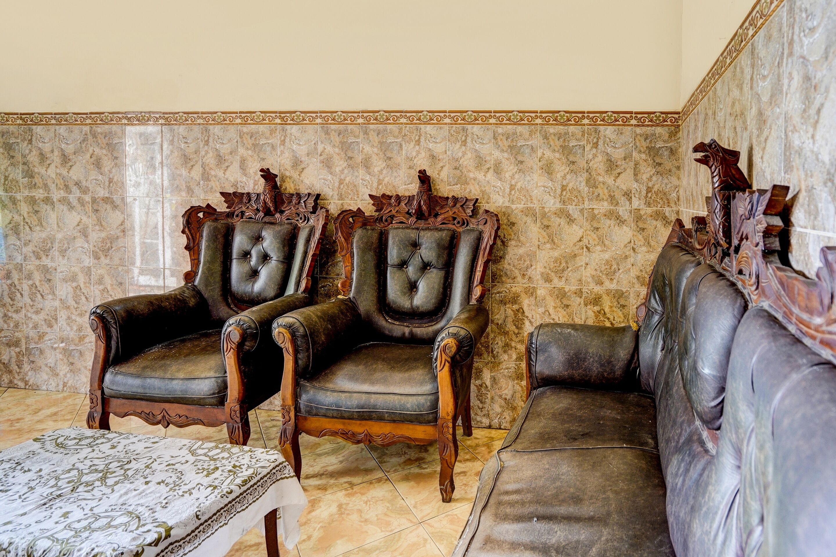 Una stanza con due poltrone in pelle finemente decorate e un divano.