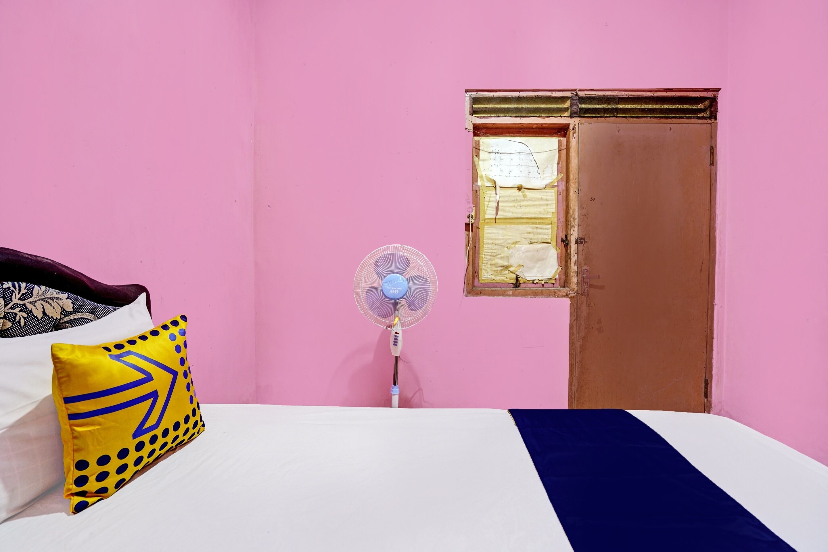 Una camera da letto con un letto, una ventola, una finestra e una porta.