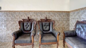 A room with three leather armchairs and a sofa, arranged against a tiled wall. - Hotel O Nurul Homestay Syariah (Gresik)