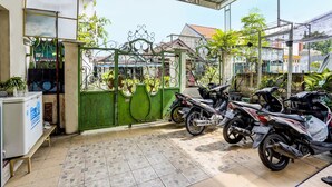 A covered parking area with a green gate, a refrigerator, and several motorcycles parked inside. - Hotel O Nurul Homestay Syariah (Gresik)