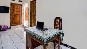 A room with a wooden table, a laptop, and a chair. There are two wooden doors and a window with a view. - Hotel O Nurul Homestay Syariah (Gresik)