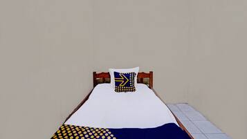 Una cama individual con colchón blanco, almohada y manta azules y amarillas.