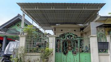 A house with a green gate, a covered porch, and potted plants.