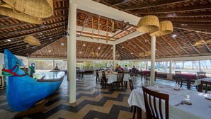 Un restaurante espacioso con techo alto, vigas de madera y cestas colgantes. Las mesas están dispuestas con manteles blancos y sillas.