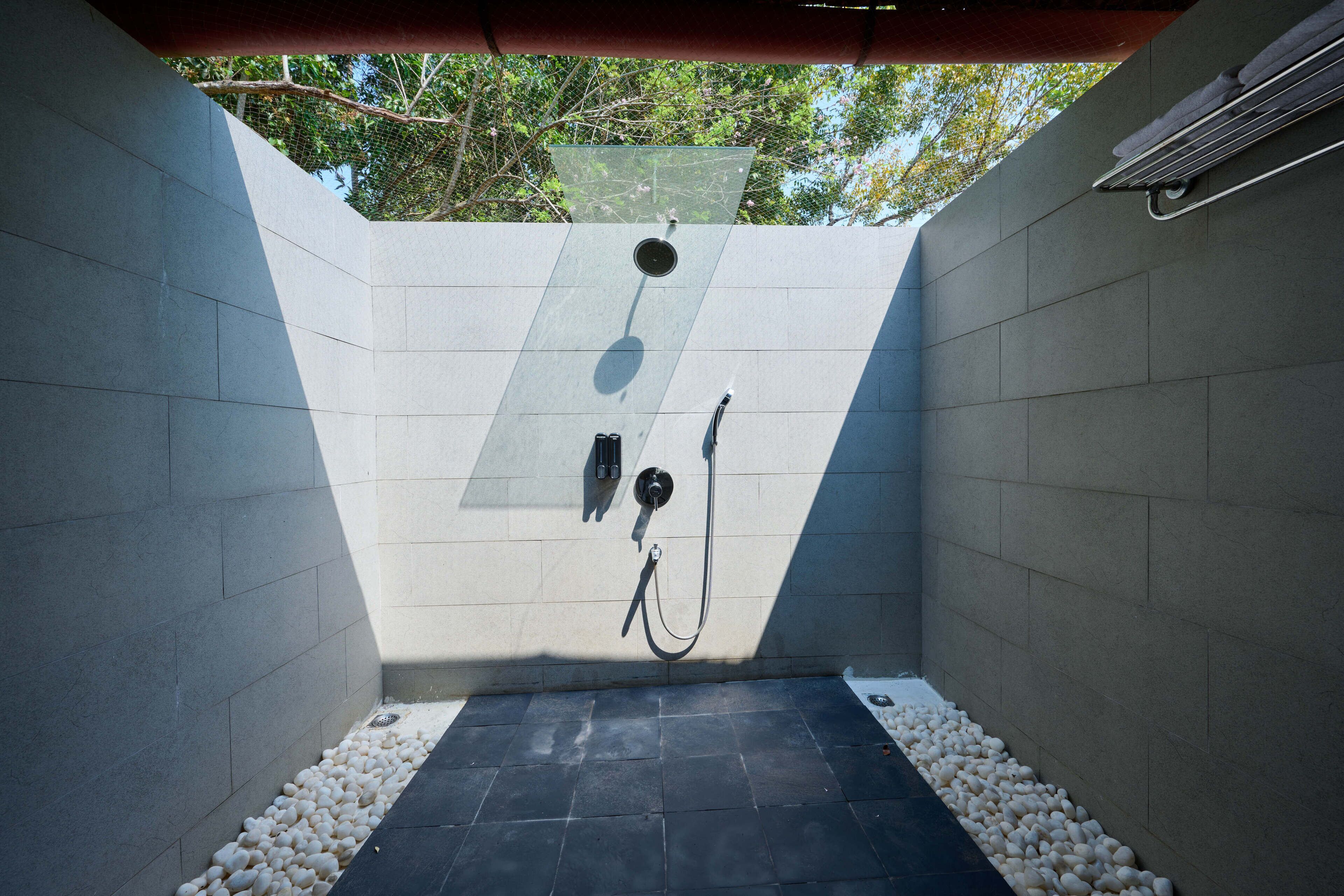 A modern shower area with a tiled floor, a showerhead, and a hose.