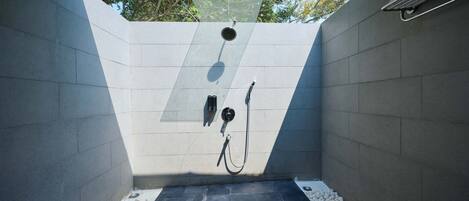 A modern shower area with a tiled floor, a showerhead, and a hose.